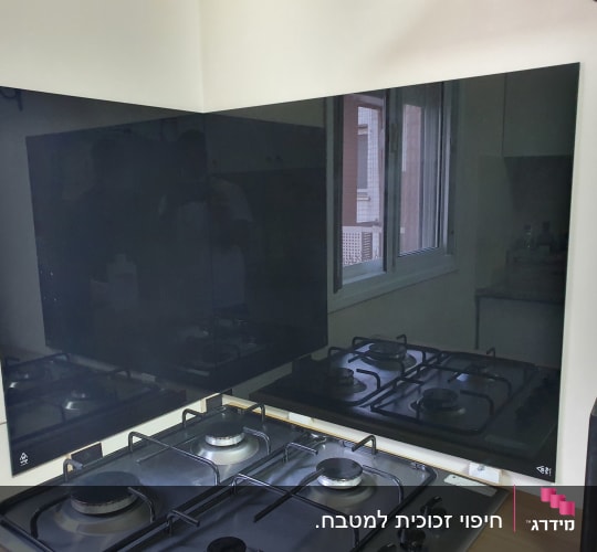 זכוכית כהה משתקפת מעל כיריים במטבח